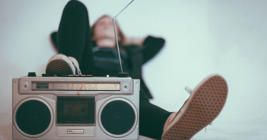 Jovem deitado com os pés sobre um aparelho de rádio