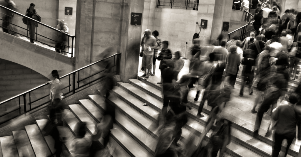 Imagem em tons de cinza mostra diversas pessoas andando em uma escada